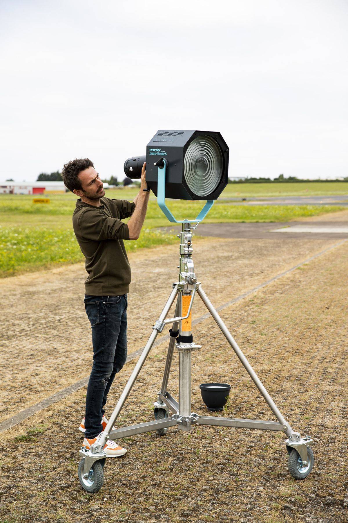 Photographer aiming a Flooter on a wind-up stand at an airfield